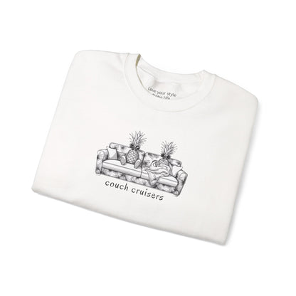 A folded white crewneck sweatshirt featuring a black line art graphic of a couch with pineapples and the text 'couch cruisers' underneath, displayed on a clean white background.