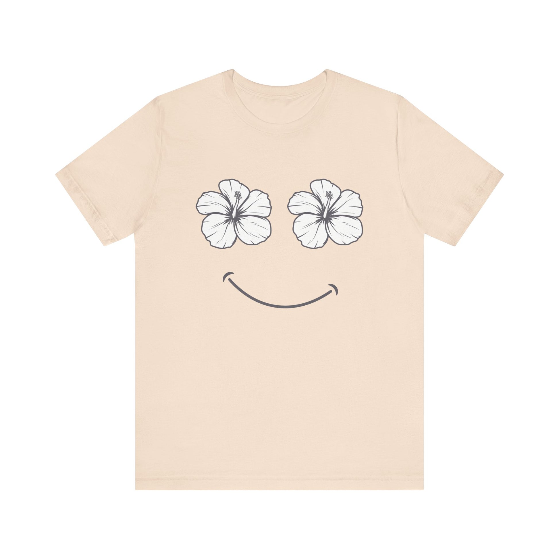 A light beige crewneck t-shirt featuring a graphic of two white hibiscus flowers forming eyes and a simple smile on the front, displayed against a solid white background.
