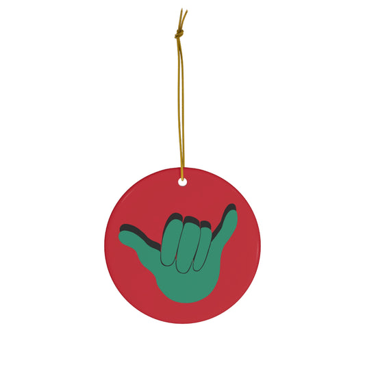 Red ceramic Christmas ornament featuring a green shaka hand design with black outline.