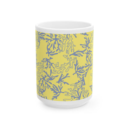 A white ceramic mug featuring a yellow wrap-around sleeve with a blue coral pattern, shown on a clean white background.