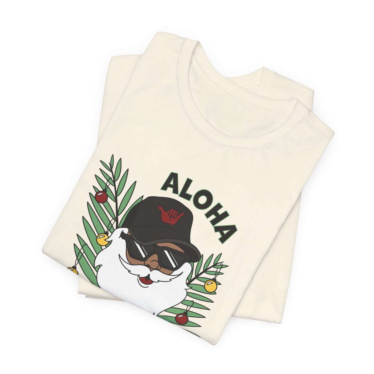 Folded Natural Santa Kalikimaka unisex T-shirt with hand-drawn Santa wearing sunglasses and throwing a shaka surrounded by tropical palm leaves.