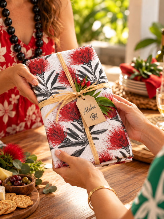 Red ʻŌhiʻa lehua kitchen towel wrapped as a hostess gift and being handed to a friend.