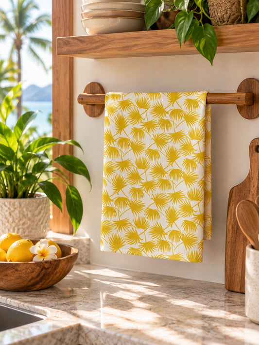 Fan Palm Sunshine kitchen towel folded over a wooden towel rail in a bright tropical Hawaiʻi kitchen.