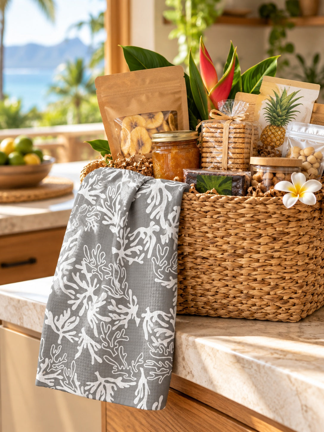 Coral Sharkskin Grey kitchen towel draped over a gift basket filled with local-style foods in a tropical Hawaiʻi kitchen.