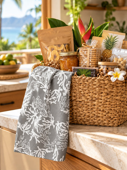 Coral Sharkskin Grey kitchen towel draped over a gift basket filled with local-style foods in a tropical Hawaiʻi kitchen.