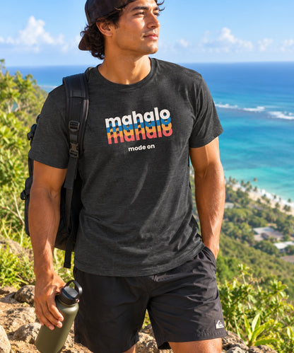 Man wearing a black retro Mahalo Mode graphic t-shirt while hiking above the ocean in Hawaiʻi.