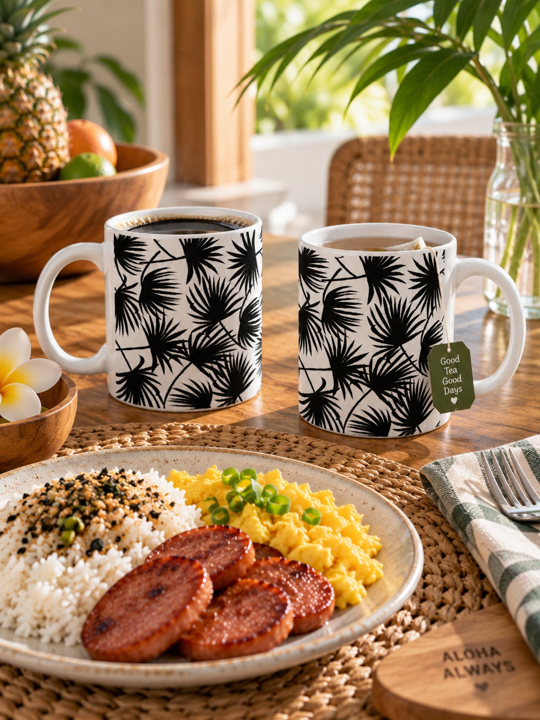Two Palm Fan Black ceramic mugs with coffee and tea beside a local-style breakfast of eggs, rice and Portuguese sausage.