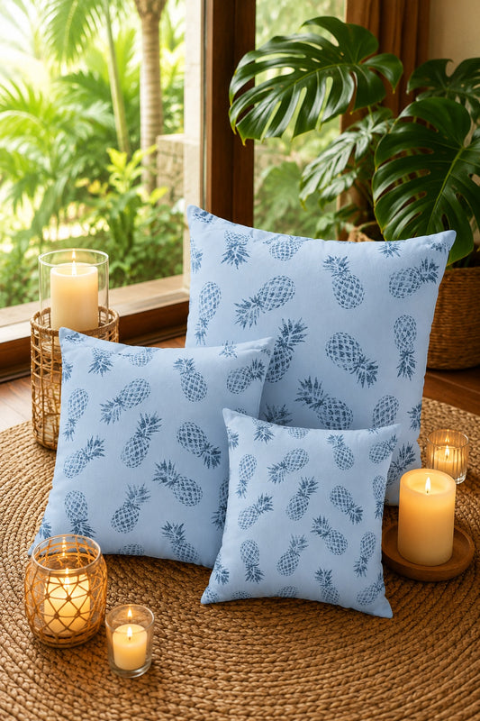3 sizes of blue pineapple square pillows on rattan mat surrounded by candles