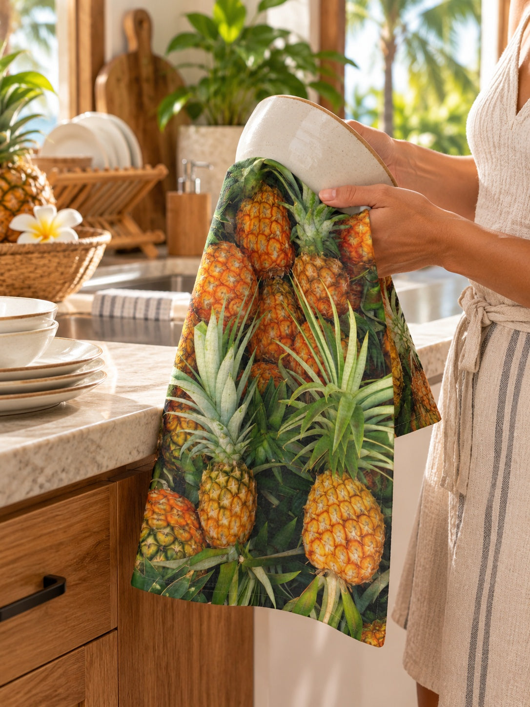 Pineapple print kitchen towel being used to dry a ceramic bowl in a tropical Hawaiʻi kitchen.