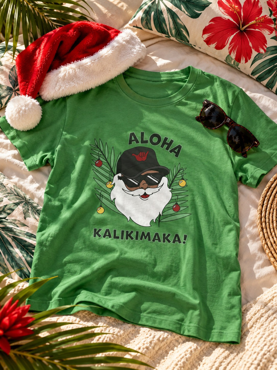 Green Aloha Kalikimaka Santa graphic tee styled with a Santa hat and sunglasses in a tropical holiday setting.