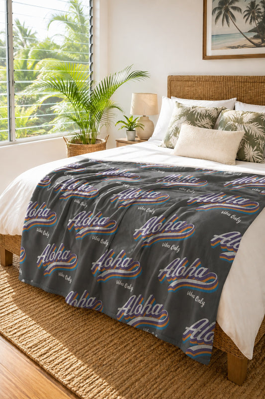 aloha vibes gray sherpa fleece blanket draped on a tropical bed