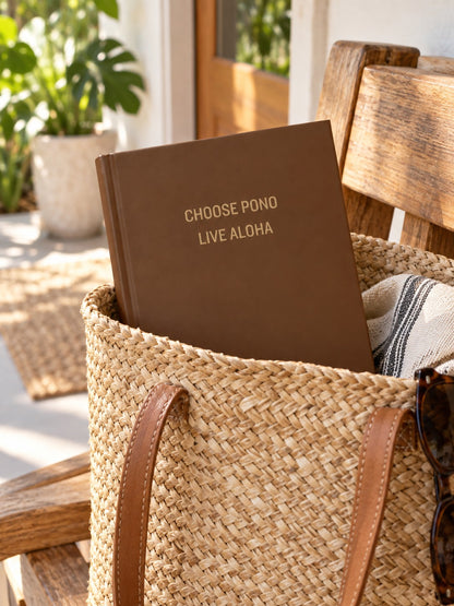 Brown Choose Pono Live Aloha hardcover journal tucked inside a woven straw tote in a bright tropical home.