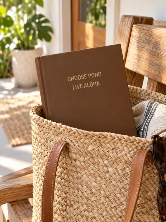 Brown Choose Pono Live Aloha hardcover journal tucked inside a woven straw tote in a bright tropical home.