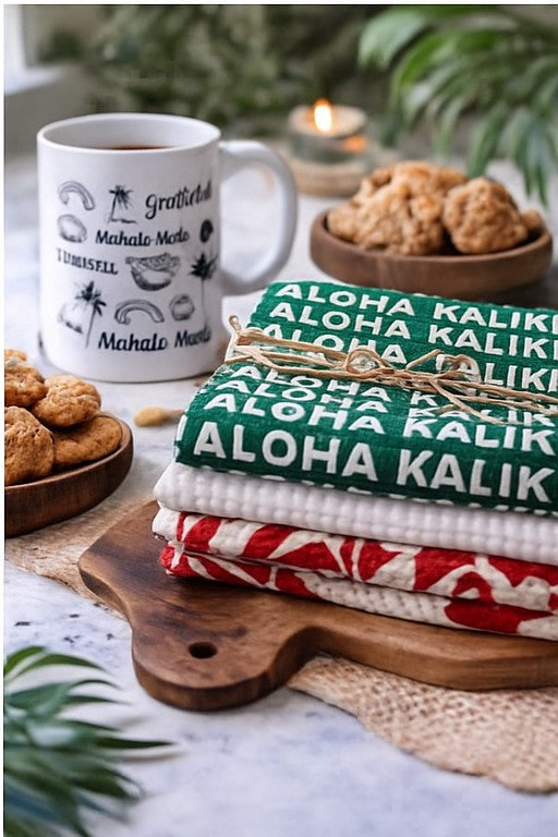 Green Aloha Kalikimaka holiday kitchen towel stacked with tropical Christmas towels and tied with twine